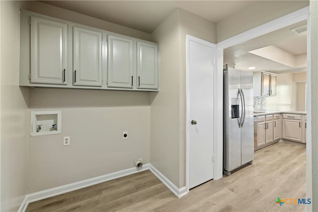 laundry area with electric dryer hookup, hookup for a washing machine, light hardwood / wood-style flooring, and cabinets