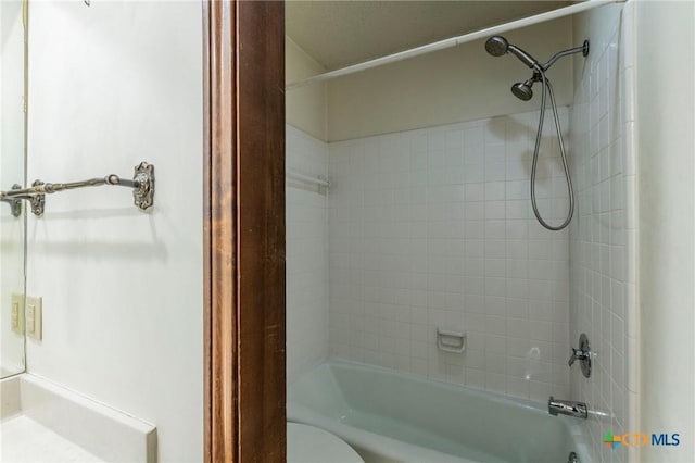 bathroom with tiled shower / bath combo and toilet