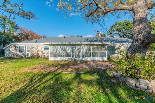 rear view of property featuring a sunroom and a yard