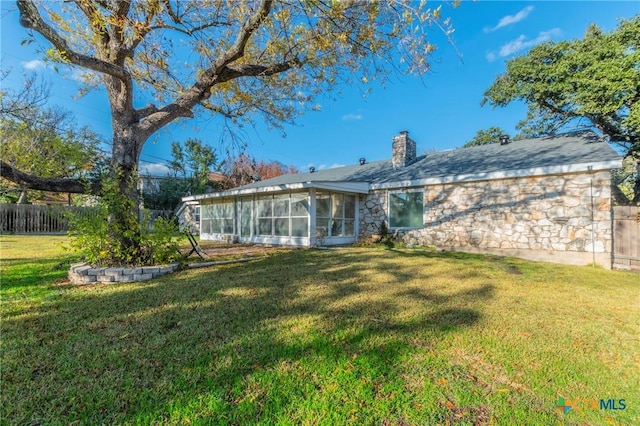 back of property with a sunroom and a yard