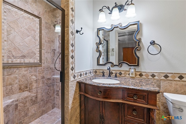 bathroom with tile walls, an enclosed shower, vanity, and toilet