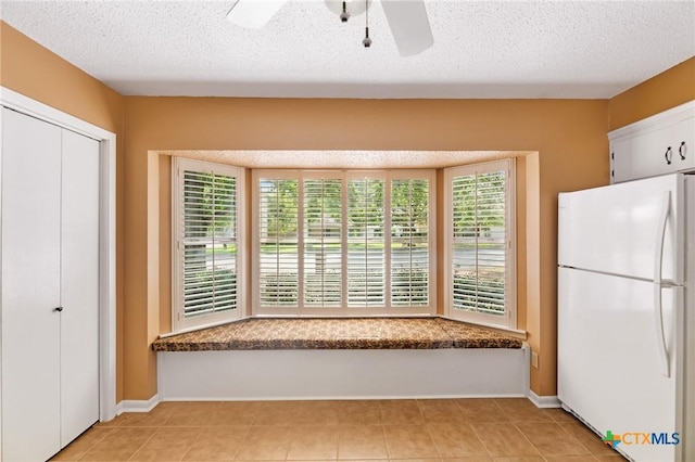 125 Hillview Dr, Luling, TX 78648 - kitchen featuring freestanding refrigerator, ceiling fan, baseboards, light tile patterned floors, and a textured ceiling