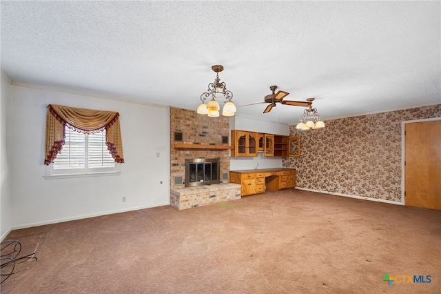 unfurnished living room featuring ceiling fan with notable chandelier, a fireplace, carpet floors, and a textured ceiling