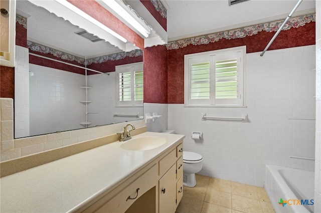 full bathroom with toilet, tile patterned floors, tile walls, tiled shower / bath, and vanity