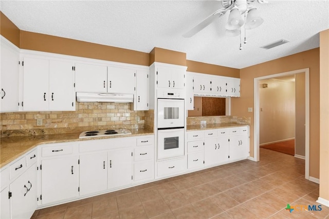125 Hillview Dr, Luling, TX 78648 - kitchen with under cabinet range hood, white appliances, tasteful backsplash, a ceiling fan, and a textured ceiling