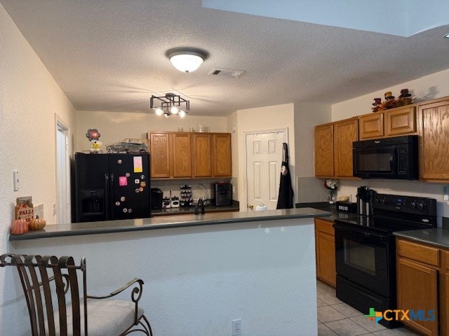 kitchen with black appliances, kitchen peninsula, a textured ceiling, and light tile patterned flooring