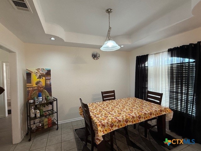 tiled dining area with a raised ceiling