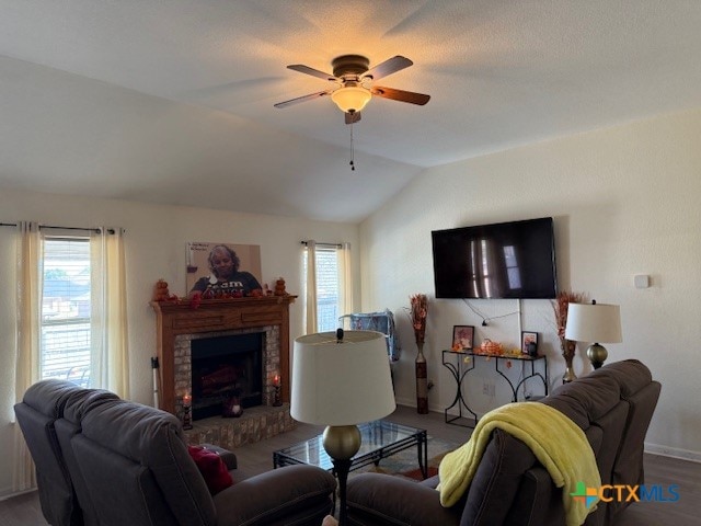 living room with a brick fireplace, hardwood / wood-style flooring, ceiling fan, and lofted ceiling