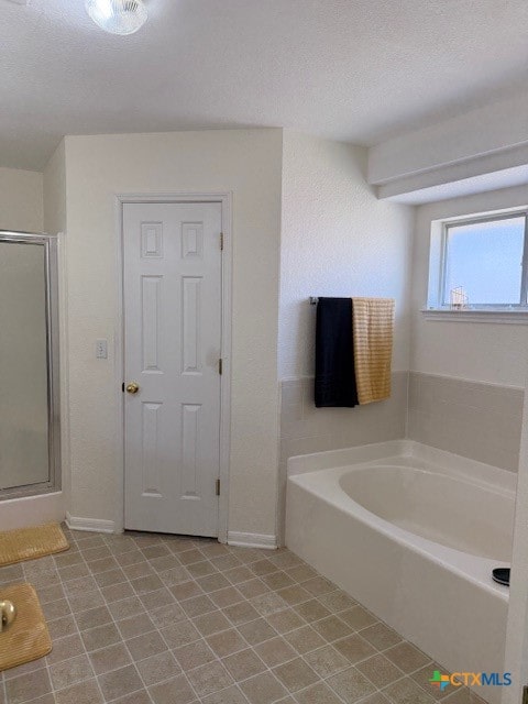 bathroom with tile patterned floors, a textured ceiling, and separate shower and tub