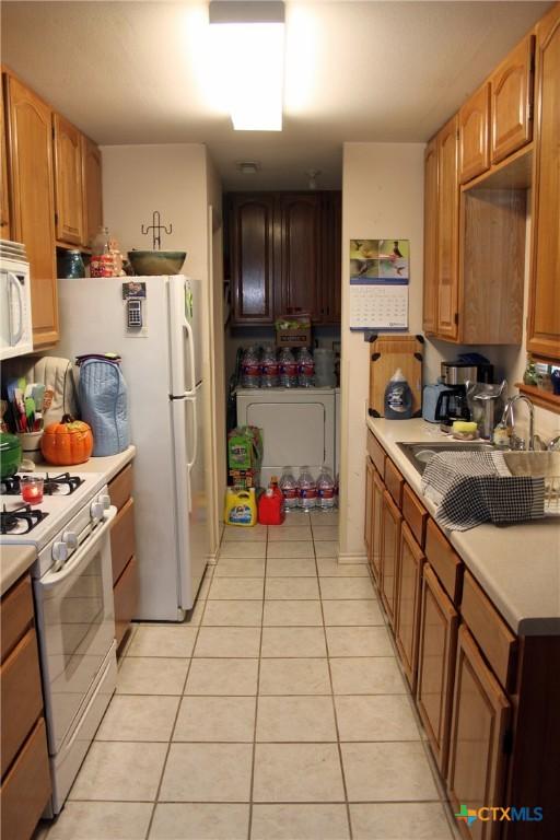 kitchen featuring white appliances, light tile patterned floors, and sink