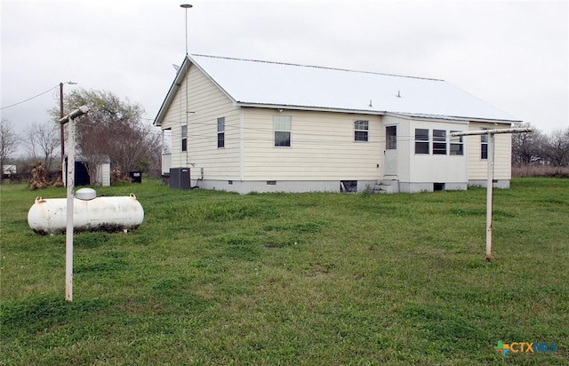 back of house featuring central air condition unit and a lawn