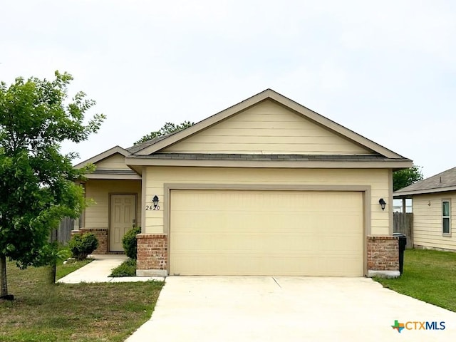 view of front of house featuring driveway, brick siding, a front yard, and a garage