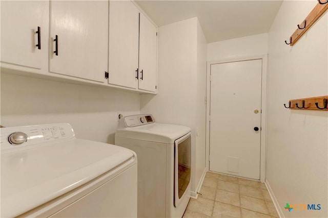 washroom with washing machine and dryer, cabinet space, and baseboards