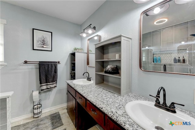 bathroom featuring double vanity, baseboards, a sink, and tiled shower