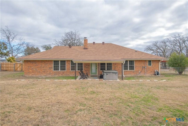 back of property with a yard, brick siding, a chimney, and a fenced backyard