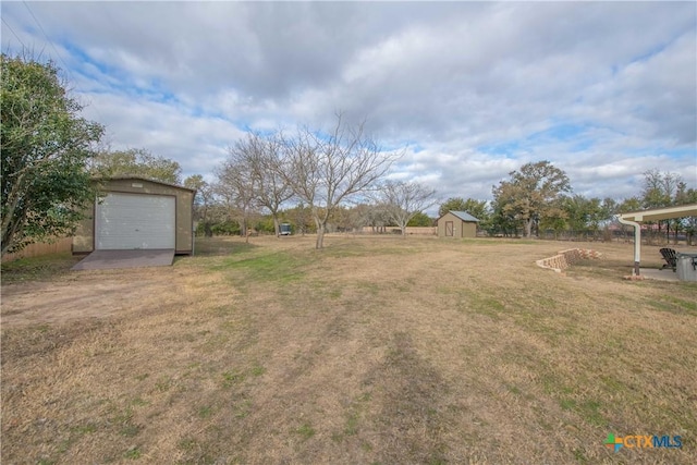 view of yard with an outdoor structure, a detached garage, and a shed