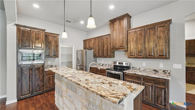 7881 Wegner Rd, New Braunfels, TX 78132 - kitchen with stainless steel appliances, dark wood-style flooring, a kitchen island, light stone countertops, and pendant lighting