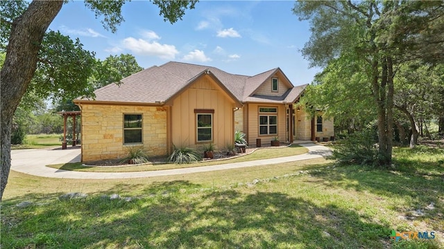 7881 Wegner Rd, New Braunfels, TX 78132 - view of front of home featuring board and batten siding, a front yard, and stone siding