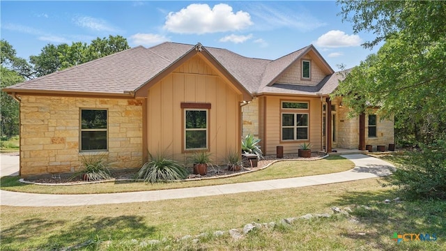 7881 Wegner Rd, New Braunfels, TX 78132 - view of front facade featuring stone siding, a front lawn, board and batten siding, and roof with shingles