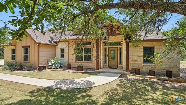 7881 Wegner Rd, New Braunfels, TX 78132 - view of front of home featuring stone siding, a front lawn, board and batten siding, and roof with shingles
