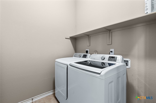 laundry area with independent washer and dryer and light tile patterned floors