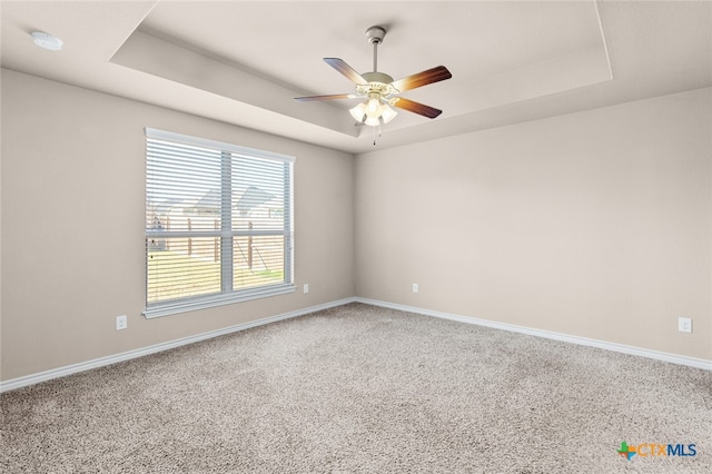 unfurnished room with carpet flooring, a tray ceiling, and ceiling fan