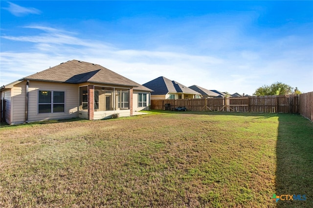 rear view of property with a sunroom and a lawn