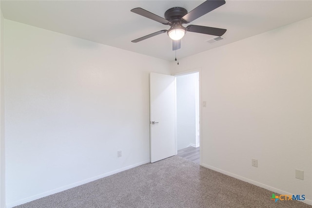 carpeted empty room featuring visible vents, a ceiling fan, and baseboards