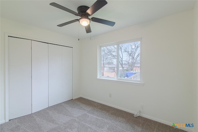 unfurnished bedroom featuring a closet, a ceiling fan, baseboards, and carpet floors