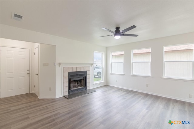 unfurnished living room featuring ceiling fan, wood finished floors, baseboards, and a tile fireplace