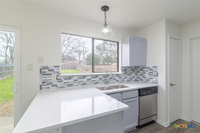 kitchen with a sink, tasteful backsplash, light countertops, dishwasher, and hanging light fixtures