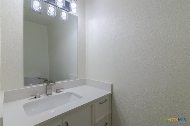 bathroom featuring vanity and a textured wall