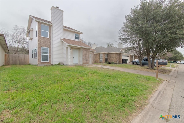 view of front facade featuring a front yard, fence, driveway, and a chimney