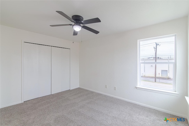 unfurnished bedroom featuring a closet, carpet flooring, a ceiling fan, and baseboards