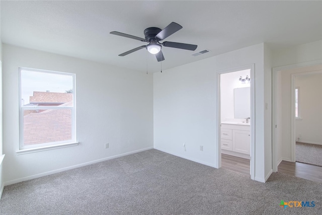 carpeted spare room with a sink, visible vents, baseboards, and ceiling fan