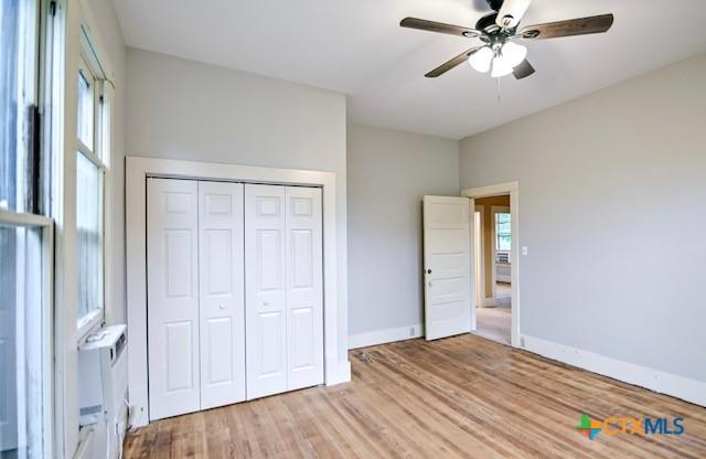 608 N Clinton St, Cuero, TX 77954 - unfurnished bedroom featuring light wood-type flooring, a closet, and a ceiling fan