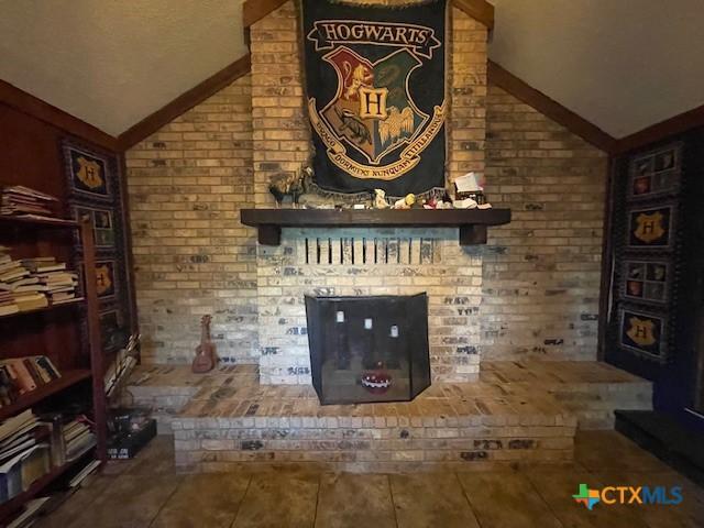 20655 State Highway 195, Killeen, TX 76542 - unfurnished living room featuring brick wall, a fireplace, and lofted ceiling