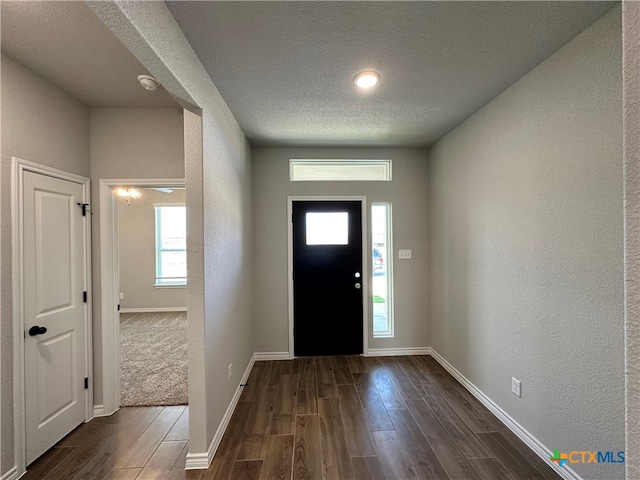 foyer entrance with dark wood-type flooring and a textured ceiling