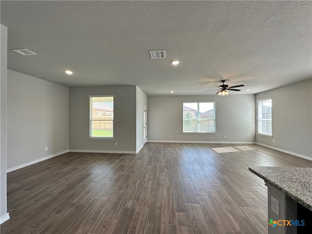 unfurnished living room with ceiling fan, a textured ceiling, and dark hardwood / wood-style floors