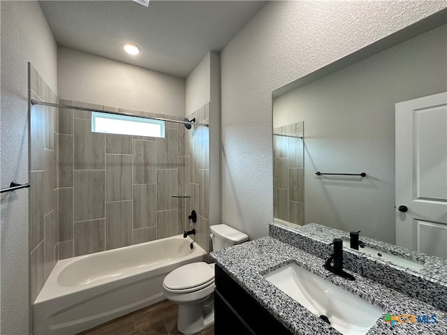 full bathroom featuring tiled shower / bath, a textured ceiling, wood-type flooring, vanity, and toilet