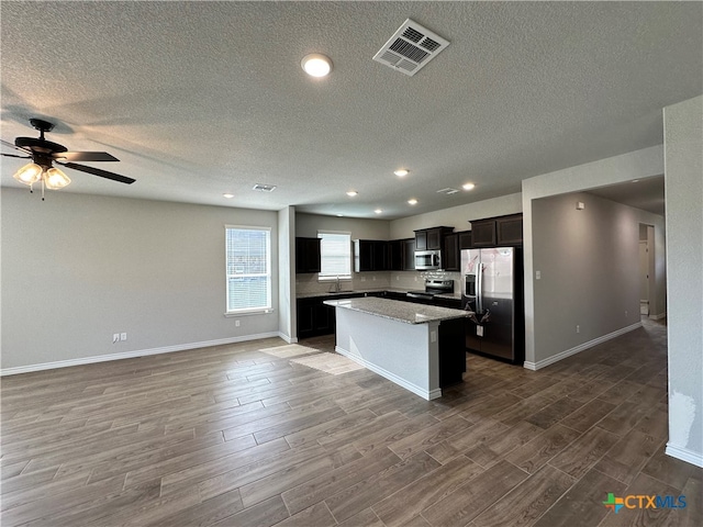 kitchen featuring stainless steel appliances, a center island, a textured ceiling, sink, and dark hardwood / wood-style floors