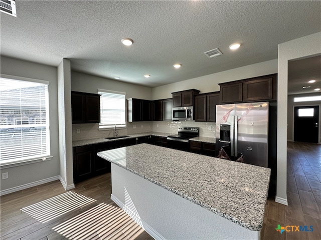 kitchen with stainless steel appliances, dark hardwood / wood-style floors, decorative backsplash, and a kitchen island