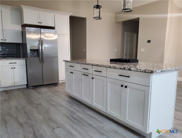 kitchen with a center island, stainless steel refrigerator with ice dispenser, hanging light fixtures, white cabinetry, and light wood-type flooring