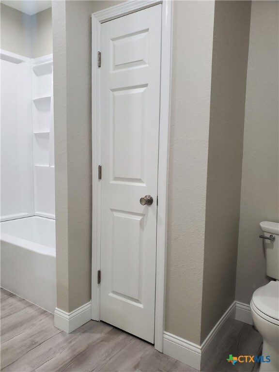 bathroom featuring toilet, bathtub / shower combination, and wood-type flooring