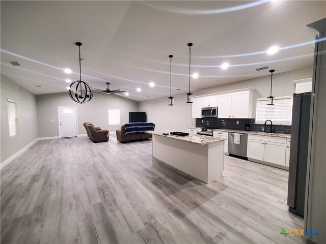 kitchen with light hardwood / wood-style floors, stainless steel appliances, a center island, white cabinets, and decorative light fixtures