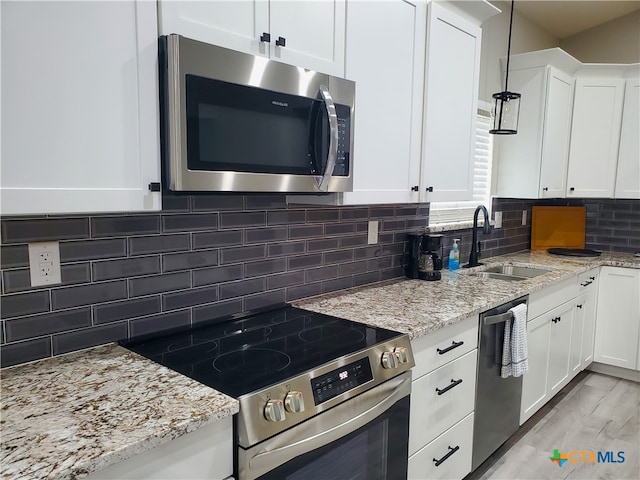 kitchen featuring stainless steel appliances, sink, tasteful backsplash, light stone countertops, and white cabinetry