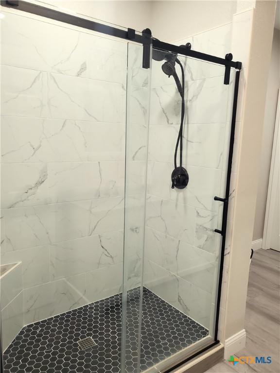 bathroom featuring wood-type flooring and a shower with shower door