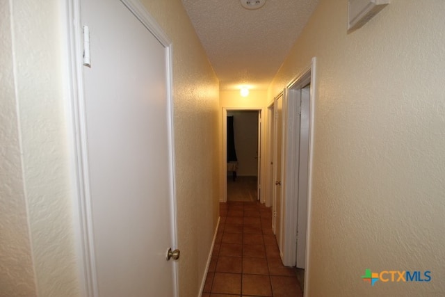 corridor featuring dark tile patterned flooring and a textured ceiling