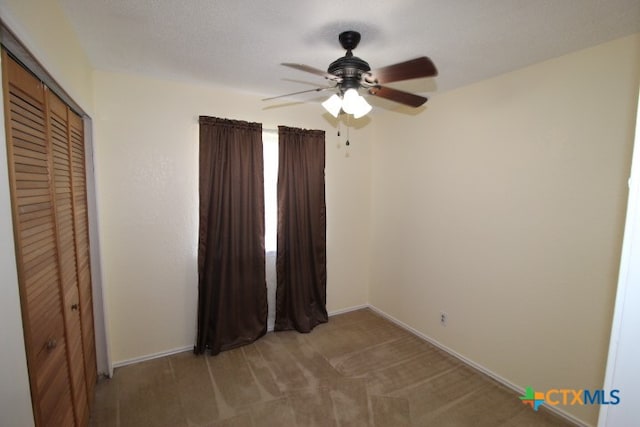 unfurnished bedroom featuring light carpet, ceiling fan, and a closet