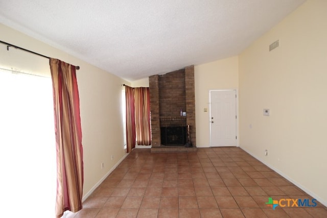 unfurnished living room with a brick fireplace, a textured ceiling, light tile patterned floors, and lofted ceiling